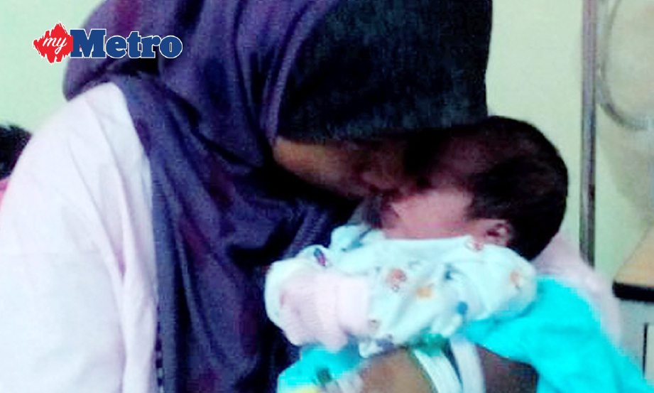 ISTERI kepada Allahyarham Mohd Zaini Harun, 38, mencium anak bongsu mereka, masih terkejut dengan apa yang berlaku. FOTO Siti Nadzirah Che Mud