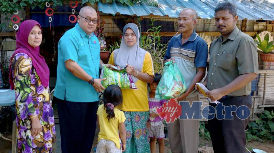 PEGAWAI JKM Baling, Shamsul Izrin Isahak (dua kiri) menyampaikan barangan makanan kepada Rokiah Hashim, di rumahnya Kampung Banggol Enggok, Mukim Bakai. FOTO Ihsan JKM