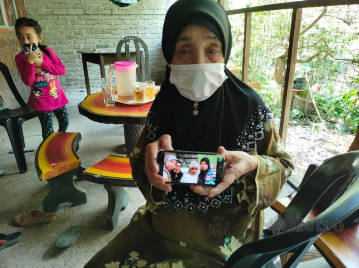 Ibu mangsa kemalangan, Hasmah Sohor menunjukkan gambar terakhir anak bongsunya, Nor Hayati Abdullah (dalam gambar, tudung hitam, kanan) ketika ditemui di rumahnya di Kampung Jerang Belanga, Bagan Terap, hari ini. FOTO AMIRUL AIMAN HAMSUDDIN 