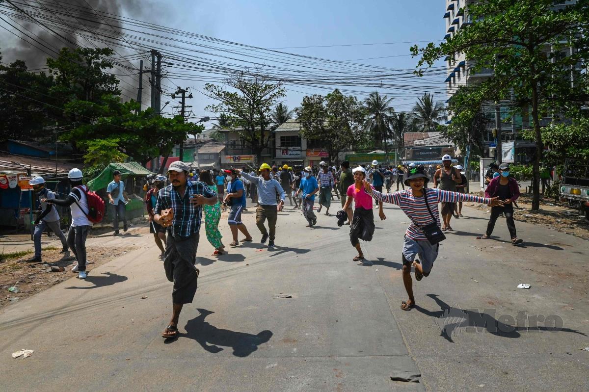 Perusuh berlari daripada pihak berkuasa di bandar Yangon. FOTO AFP