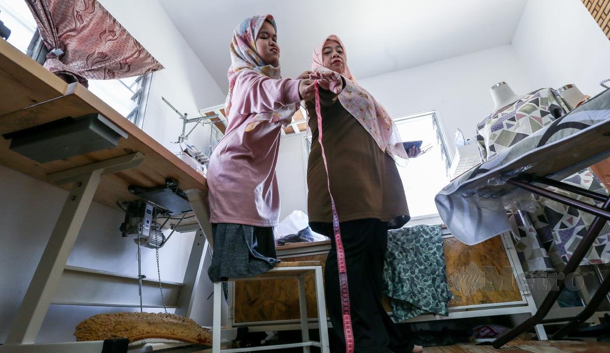 Tukang jahit kerdil, Nurul Izzah Mohd Asri, 26, berketinggian 120 sentimeter (cm) terpaksa mengambil ukuran pelanggan dengan bantuan kerusi ketika menerima tempahan menjahit baju raya di Kampung Petani Merbau Kudung, Tasek Gelugor. FOTO DANIAL SAAD