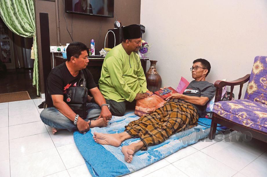 MOHD Hamidi (tengah) beramah mesra dengan Ab Karim ketika melawat rumahnya di Kampung Rahmat.