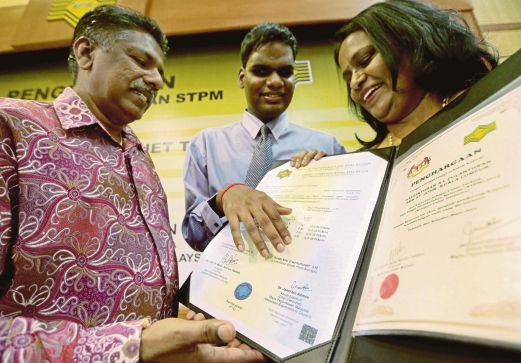  KAVEINTHRAN menyentuh keputusan STPM dalam tulisan Braille sambil diperhatikan ibu, Thanamala Muniandy, 50, dan bapanya  Pulanthran Muniandy, 56,  di Selayang, semalam.