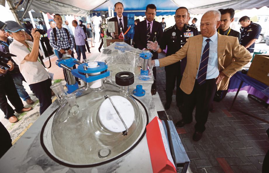 MOHMAD  (kanan) menunjukkan  mesin memproses dadah  yang dirampas dalam serbuan di Johor. 