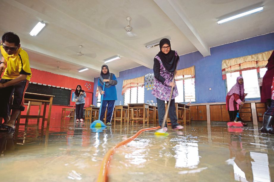 KAKITANGAN sekolah, guru dan pelajar bergotong-royong membersih kawasan yang dinaiki air di Sekolah Kebangsan Matang. 