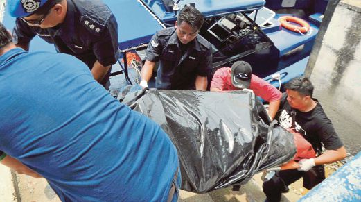 ANGGOTA Polis Marin mengangkat mayat mangsa karam bot tunda di jeti Polis Marin Padang Lalang, semalam.