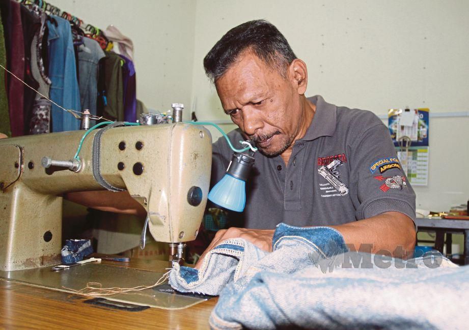 BAHARUDIN menjahit dan mengubah suai seluar pelanggan di kedainya di Bazar Tok Guru.
