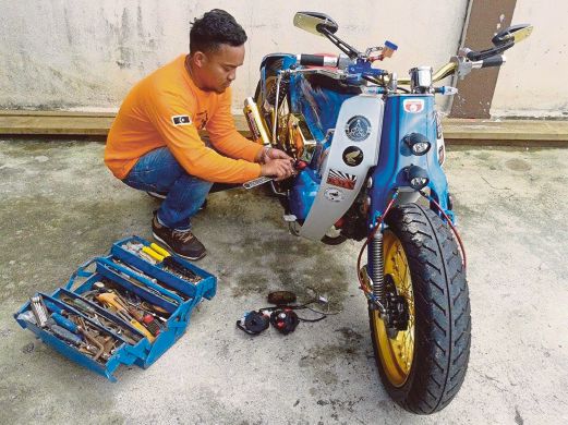 FIRDAUS sedang menyiapkan motosikal Street Cub ditempah pelanggannya.