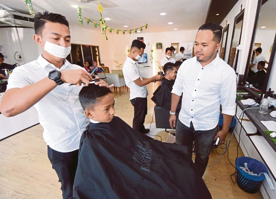 MOHD Yusof  (kanan) melihat kakitangannya menggunting rambut pelanggan di Matt Barber Shop.