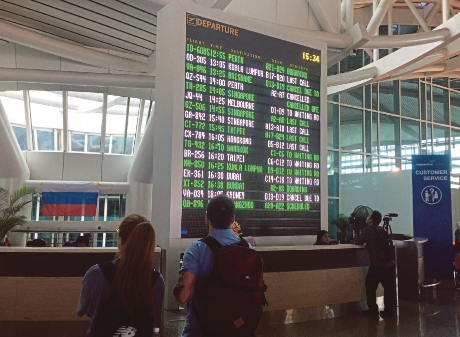PENUMPANG melihat papan maklumat penerbangan di Lapangan Terbang Antarabangsa Ngurah Rai di Bali semalam. - Agensi