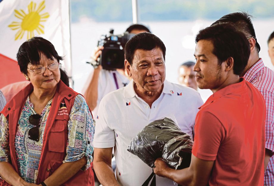 DUTERTE (tengah) menyerahkan bekalan kepada nelayan Vietnam ketika menghadiri majlis melepaskan  sekumpulan nelayan Vietnam pulang di Sual, utara Manila, semalam.  Seramai 17 nelayan Vietnam itu ditahan 8 September lalu kerana didakwa menangkap ikan di perairan Filipina.  - EPA