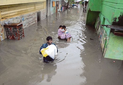 PENDUDUK mengharung banjir di Chennai, semalam.  