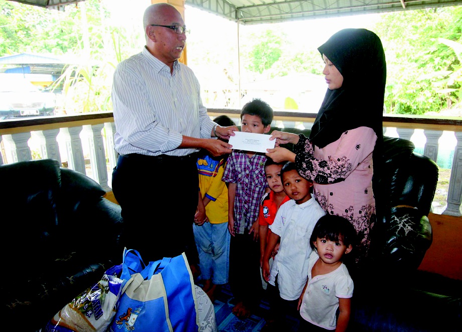 MOHD Noh  menyerahkan cek sumbangan  kepada Shila  ketika berkunjung ke kediamannya di Kampung Gunung Lambak 2, Kluang.