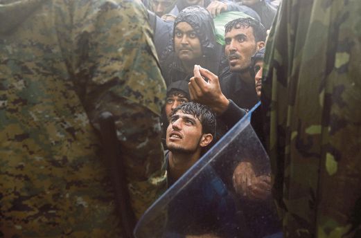 PENDATANG merayu polis Macedonia membenarkan mereka memasuki sempadan dari Greece dalam keadaan hujan lebat di Idomeni.