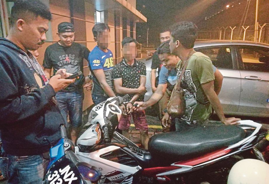 REMAJA OKU  dan rakannya (tengah) disoal anggota trafik selepas  ditahan, semalam.  