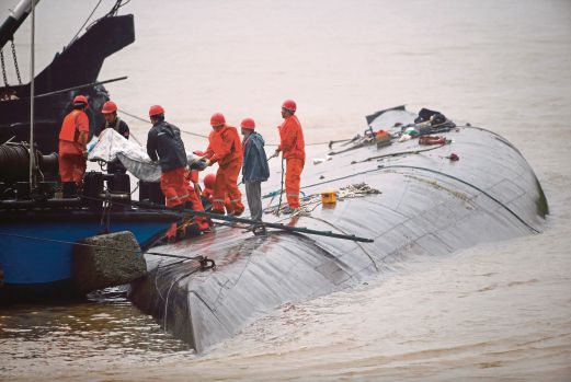 PASUKAN penyelamat membawa keluar mayat dari bot yang karam.