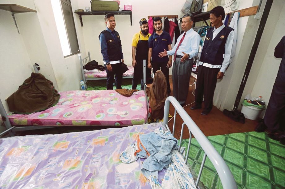   Wan Zulkifli  (dua  dari kanan) melihat bilik  pekerja asing ketika   operasi penguatkuasaan, semalam. 