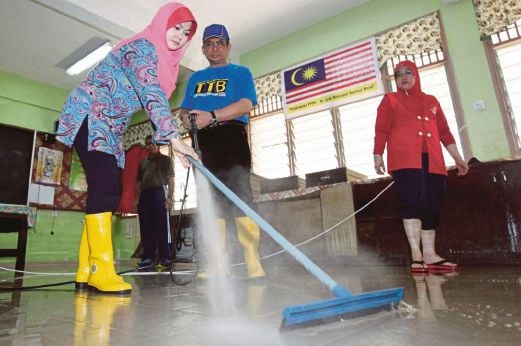 AHMAD Razif dan isteri To' Puan Halina Zakaria (kiri) membantu membersihkan lantai di dalam kelas yang dipenuhi lumpur. 