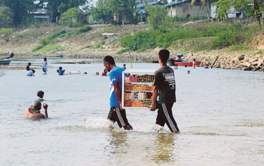 PENDUDUK daripada Kampung Bering, Thailand sempat membawa barang makanan untuk dijual ketika orang ramai sibuk menyeberangi sungai yang semakin kering ke pekan Rantau Panjang.