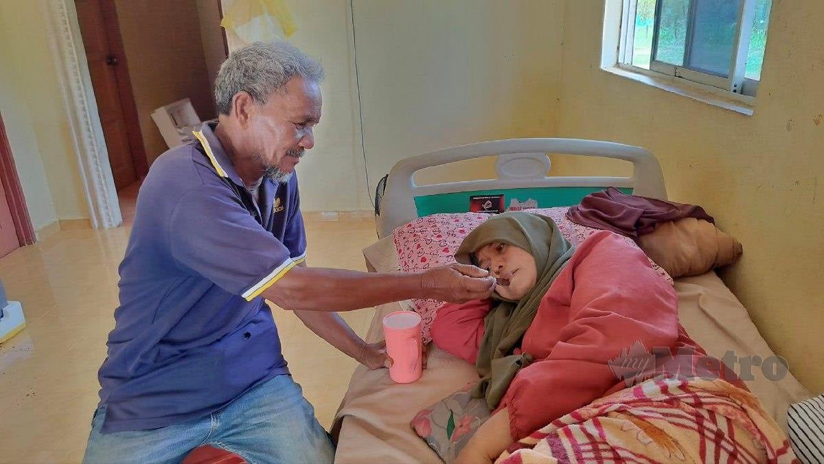 Md Daud Ahmad menyuap minuman kepada isterinya, Khalijah Hashim yang menghidap kanser payu dara tahap empat hingga tidak dapat bergerak. FOTO ZULIATY ZULKIFFLl