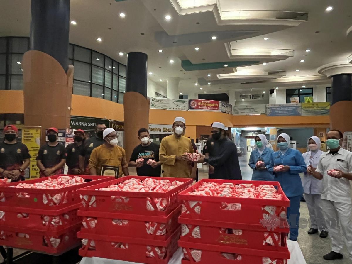 Mohammad Yaakub Yusra (berbaju coklat) menyerahkan 400 burger kepada Timbalan Pengarah Hospital Sultan Abdul Halim (HSAH) Dr Mohamed Ali (baju hitam), malam tadi. FOTO IZAD THAQIF HASSAN
