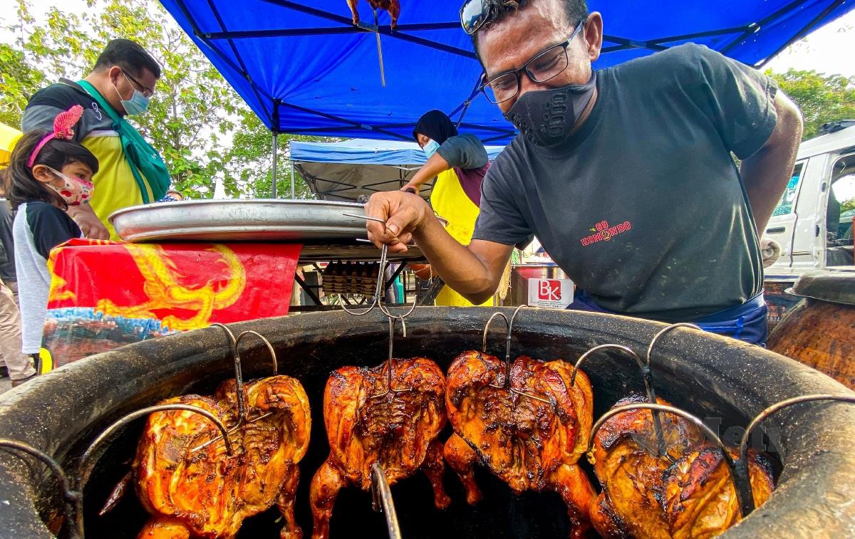 Peniaga ayam tempayan, Mohd Roshan Mohd Radzi, membakar ayam yang disalut madu dalam tempayan di bazar ramadan Stadium Darul Aman. FOTO LUQMAN HAKIM ZUBIR