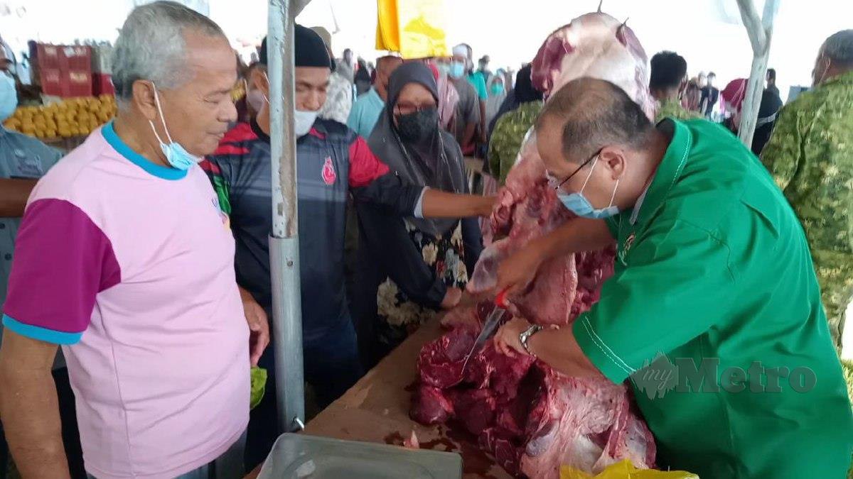 Ahmad Amzad (kanan) memotong daging lembu pada PJKM di Padang Bola Kampung Durian Burong, hari ini. FOTO BAHAROM BAKAR.