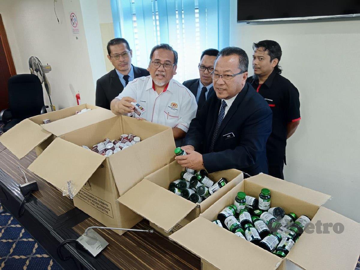 Pengarah Jabatan Kesihatan Negeri (JKN) Pahang, Datuk Dr Rusdi Abd Rahman (tengah) menunjukkan produk ubat-ubatan tidak berdaftar dan kosmetik tidak bernotifikasi yang dirampas di Kuantan. FOTO Asrol Awang