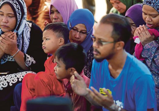 KHAIRUL Shafiq bersama isteri dan anaknya mengaminkan bacaan doa  pada majlis pengebumian di Tanah Perkuburan Islam Tampin, semalam. 