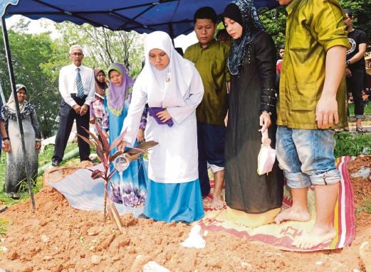 NUR Diyana (tengah) tenang menyiram air mawar di kubur bapanya selepas selesai menduduki peperiksaan Bahasa Melayu Kertas Satu.