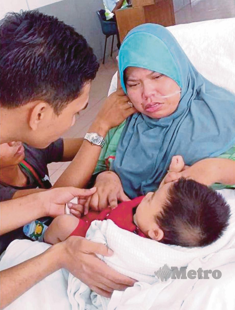MOHD Saiful membantu Norfadilla yang baru sedar daripada  koma memangku anak mereka, Muhamad Syahmi.