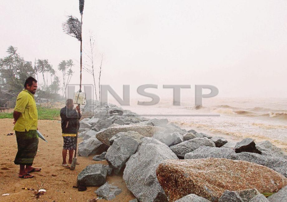ISA (kanan) bersama jirannya, Zainuddin Ismail memantau keadaan ombak besar di pesisir pantai.