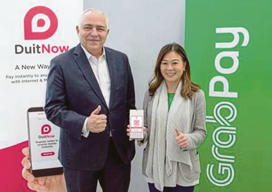 SCHIESSER (kiri) dan Pengarah Urusan GrabPay Malaysia, Singapura dan Filipina, Ooi Huey Tyng selepas menandatangani kerjasama menjadikan GrabPay sebagai e-dompet pertama mengguna pakai DuitNow QR.