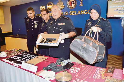MOHD Adnan (dua dari kanan) menunjukkan antara barangan milik suspek yang dirampas.