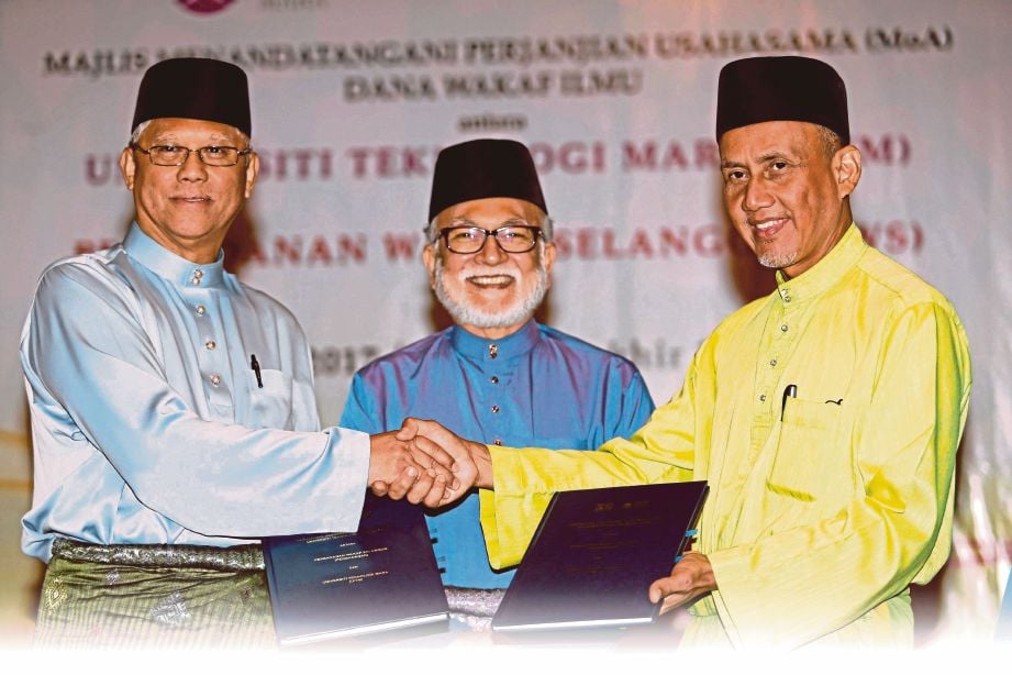 DR Hassan (kiri) bertukar dokumen dengan Abu Bakar (kanan) disaksikan Ahmed Zaidee (tengah) pada majlis memorandum perjanjian Dana Wakaf Ilmu UiTM bersama Perbadanan Wakaf Selangor. 