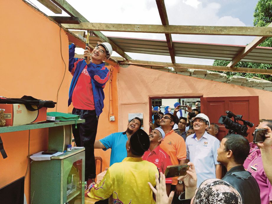 MOHD Ali (kiri) turut serta dalam kerja baik pulih rumah di Taman Bukit Piatu Mutiara.