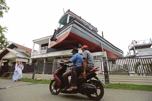 KAPAL yang tersadai di atas bumbung rumah selepas dilanda tsunami menjadi tarikan pelancong. 