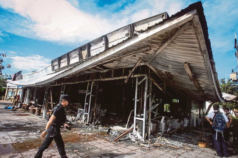 ANGGOTA polis berkawal di sebuah kedai serbaneka yang musnah dalam serangan bom di Pattani, kelmarin. - AFP