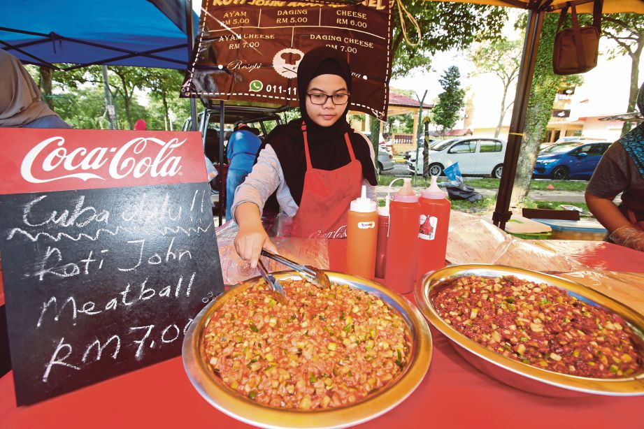NUR Syuhadah menyediakan inti “ Roti John Meatball” di Bazar PPR Batu Muda, Kuala Lumpur.
