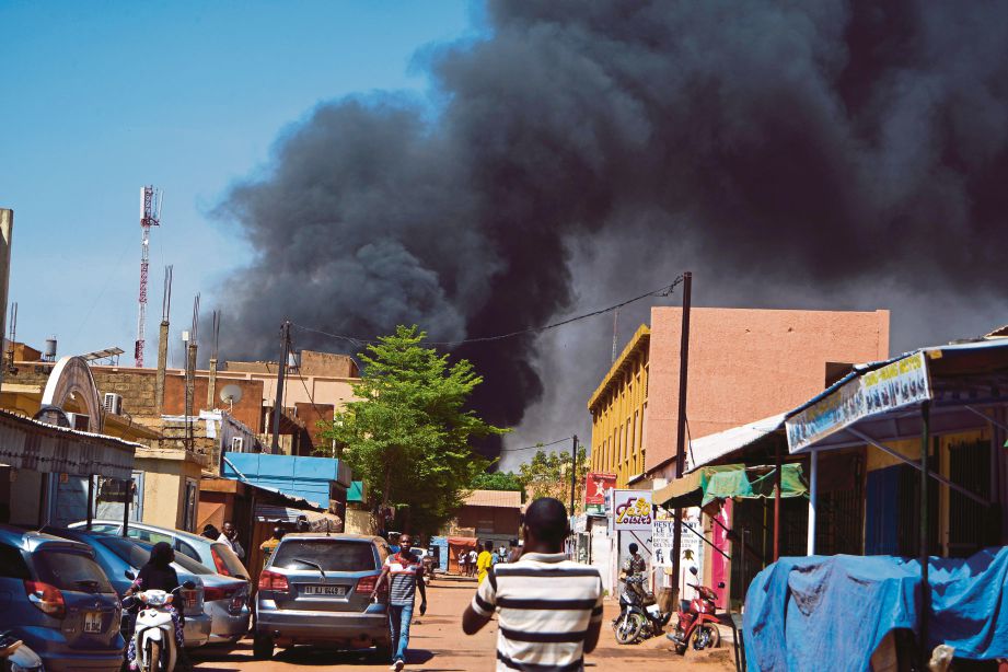 ORANG ramai melihat asap tebal akibat serangan di Ouagadougou. - EPA