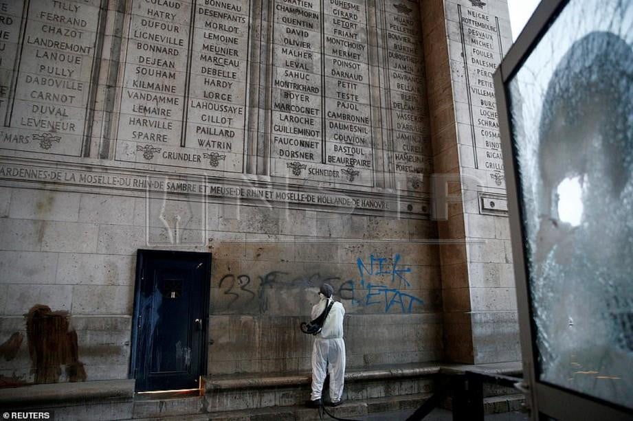 PEKERJA membersihkan cat yang disembur di tugu peringatan Arc de Triomphe. - Daily Mail