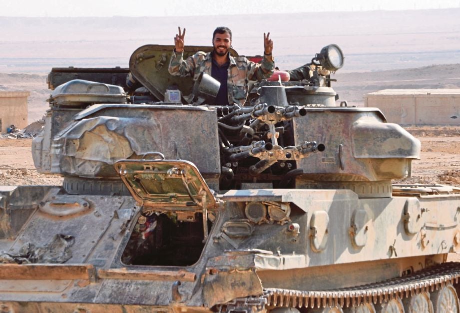 SEORANG askar kerajaan Syria menunjukkan tanda kemenangan di Deir Ezzor selepas mengusir sepenuhnya Daish dari situ. - AFP  