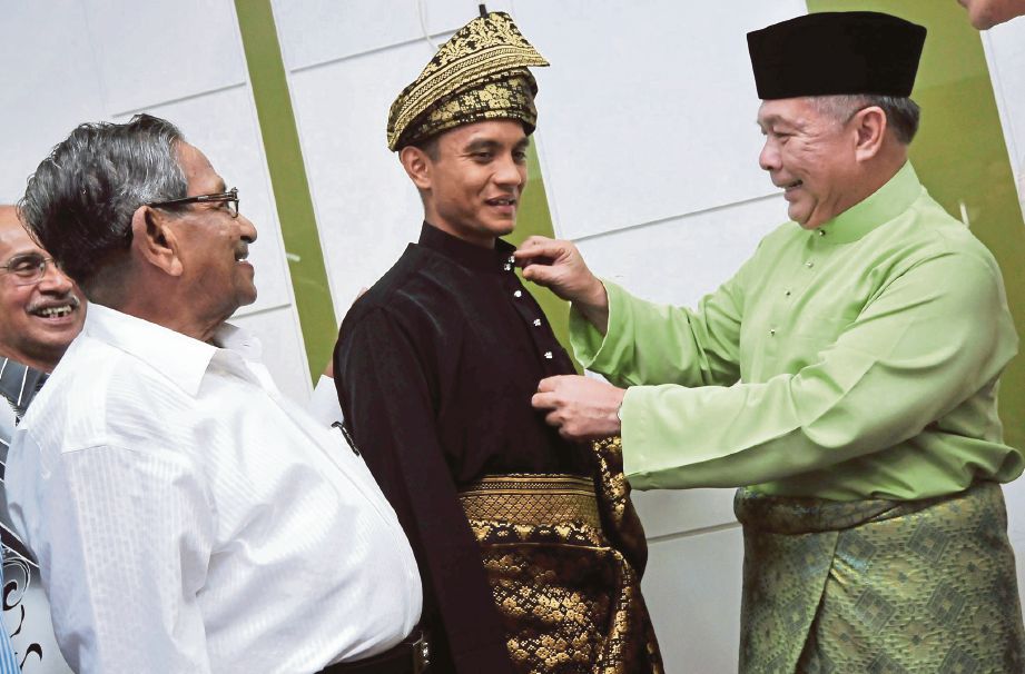 ABDUL  Latiff   (kanan) memperkemaskan pakaian tradisional Melayu yang dipakai  Faiz   selepas majlis penyerahan pakaian itu di Pulau Pinang, semalam.