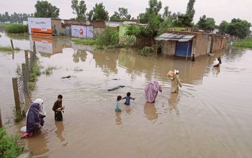 Penduduk kampung meredah   banjir di Nowshera berhampiran Peshawar, Pakistan.