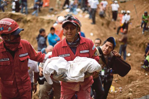 SEORANG petugas penyelamat menggendong mayat bayi yang terbunuh dalam kejadian tanah runtuh, semalam. 
