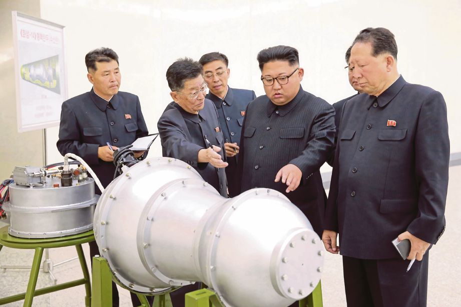 GAMBAR menunjukkan Jong Un (dua dari kanan) memeriksa model bom hidrogen yang didakwa boleh dibawa peluru berpandu rentas benua. - AFP