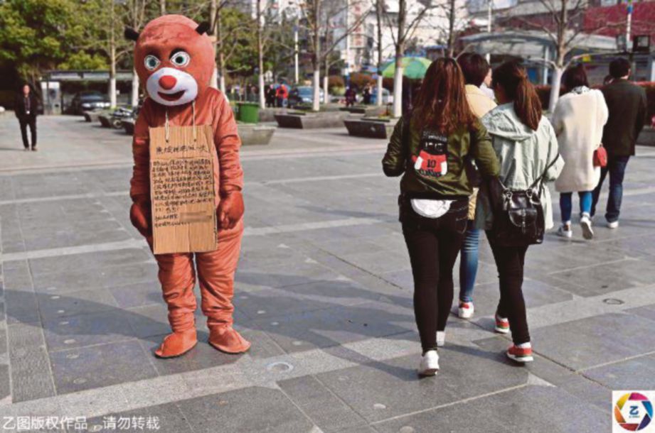 FENG memakai kostum beruang berdiri di  jalan raya di Hefei, menanti mereka yang mahu dipeluknya untuk memungut derma bagi membayar kos rawatan anaknya.  - Agensi 