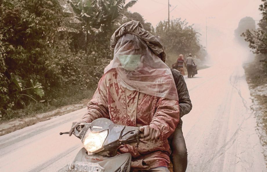 PENUNGGANG motosikal menutup muka dengan plastik selepas debu dari gunung Sinabung menyelubungi kampung Tiga Pancur di Karo, Sumatera Utara kelmarin. - AFP