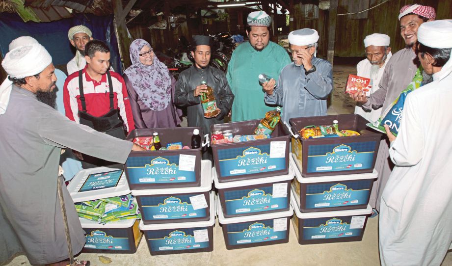 HASAN (tengah) bersama penghuni Madrasah Diniah Ihsaniah Pondok Hutan Pasir melihat kandungan Kotak Rezeki.