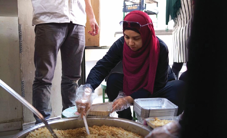 MIZZ Nina membantu mengisi nasi ke dalam bekas buat pelarian Syria.